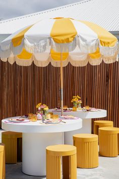 a table with yellow stools and an umbrella