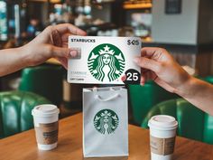 two hands holding up a starbucks gift card