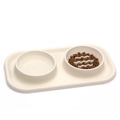 two white bowls with food in them on a tray that is shaped like a dog bowl