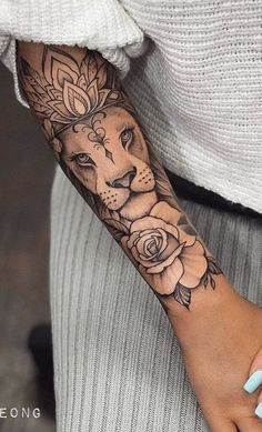 a woman's arm with a lion and roses tattoo on the left side of her arm