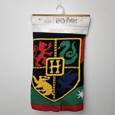 a harry potter sweater hanging from a hook on a wall with the hogwarts crest