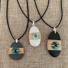 three necklaces with different designs on them sitting on top of a piece of cloth