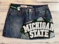 *READY TO SHIP* This ladies size 3 Michigan State University MSU themed denim patch skirt the perfect way to show support to your favorite school! I began with a size 3 gently worn Refuge brand denim skirt and have sewn Michigan State University fabrics on the front & back of the skirt along with a rescued t-shirt piece to create a unique one of a kind design!  The following details & measurements will help you decide if the fit would be right for you!  *Fabric content: 58% cotton/ 40% polyester/ 2% spandex *Waist laying flat: 14" *Around the "outside" of the waistband, through the belt loops: 29" *Hip laying flat: 17.5" *Length (measured from the side): 12" The edges of the fabric pieces will intentionally fray. This gives them the desireable "vintage" fray appearance. The more the skirt Senior Painted Jeans, Patch Skirt, Bed Party, Jeans Patch, Rush Week, Patch Denim, Painted Jeans, Michigan State University, Denim Patches