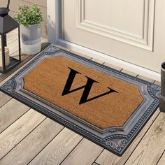 a door mat with the letter j on it next to a potted plant and lantern