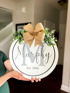 a woman holding up a sign with a bow on it that says murphy est 2004