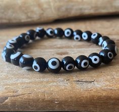 "This a simple and classy black evil eye bracelet.  It is believed that the evil eye  protects its owner from harmful energy and negativity.  Generally worn on the left wrist if you need protection over your emotions or personal life and on the right wrist if you need protection over material things such as money.  Because the left side of our body is the one linked to our emotions as it is the side of our hearts and the right side to our brain and the analytical parts of ourselves.  8mm beads 7 Handmade Symbolic Black Beaded Bracelets, Spiritual Black Evil Eye Bracelet With 8mm Beads, Black Evil Eye Bracelet With 8mm Beads As Gift, Black Evil Eye Bracelet With 8mm Beads For Gift, Handmade Symbolic Black Bracelets, Black Beaded Bracelet With Evil Eye, Black Evil Eye Bracelet With Round Beads As Gift, Handmade Black Spiritual Bracelet, Handmade Spiritual Black Bracelet