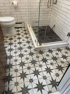 a bathroom with white and black tiles on the floor, shower stall and toilet in the corner