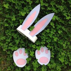 three plastic easter eggs with pink and white bunny's ears on top of green grass