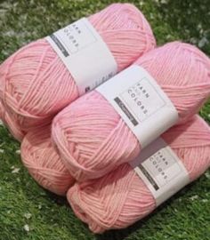 three balls of pink yarn sitting on top of green grass