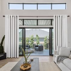 an open living room with white curtains and furniture