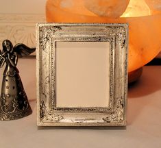 an angel figurine next to a silver frame