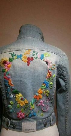 the back of a jean jacket with embroidered flowers and hearts on it's chest