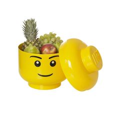 a yellow cup filled with fruit and a smiley face on the side, sitting in front of a white background