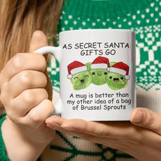 a woman is holding a coffee mug with two green heads on it and the words as secret santa gifts go