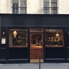 the front entrance to a restaurant with large windows and lights on it's sides