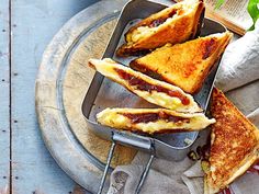 two grilled sandwiches in a pan on a plate with a fork and napkin next to it