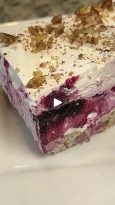 a close up of a piece of cake on a plate with nuts and blueberries