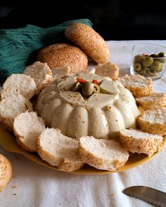 a plate with bread and olives on it next to some other food items such as crackers