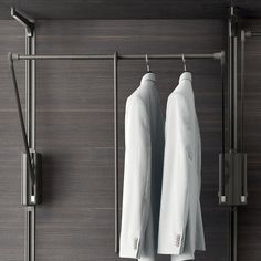 two white shirts hanging on a clothes rack in a room with dark wood paneling