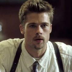 a man wearing suspenders and a white shirt is looking at the camera with an intense look on his face