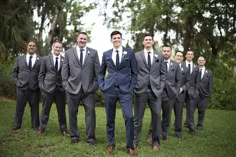 a group of men in suits standing next to each other on top of a lush green field