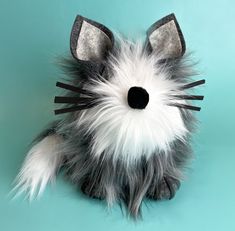 a stuffed animal that looks like a cat with black and white fur on it's face