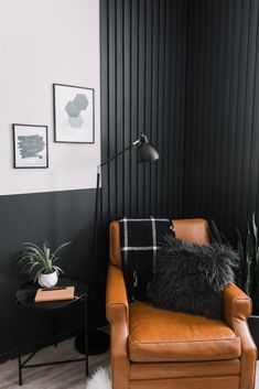 a brown leather chair sitting in front of a black wall with a white rug on top of it