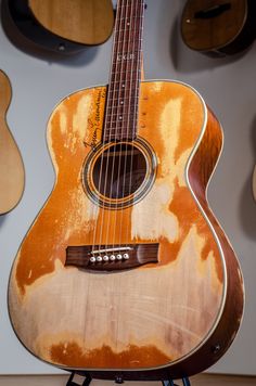 an old guitar is sitting on a stand