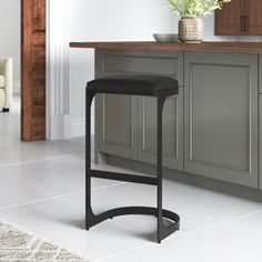 a black stool sitting in front of a counter top next to a potted plant