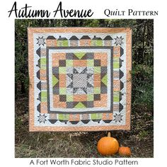 an orange and green quilt with pumpkins on the ground next to it, in front of