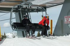 two skiers sitting on a ski lift in the snow