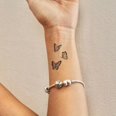 a woman's arm with a butterfly tattoo on her left wrist and two small butterflies on the right wrist