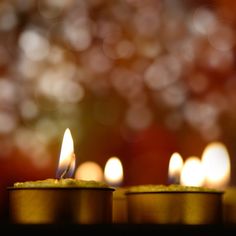 several lit candles sitting on top of each other in front of a blurry background