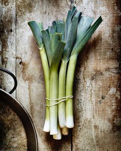 some green onions are tied up on a wooden surface and ready to be cooked in the oven