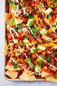 a tray filled with nachos topped with meat and cheese