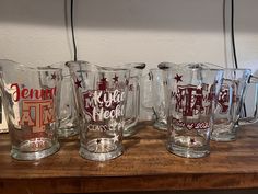 five glass mugs sitting on top of a wooden table