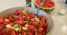 a bowl filled with sliced up tomatoes and cucumber next to a watermelon