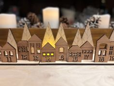 a group of wooden houses sitting next to each other on top of a table with candles in the background