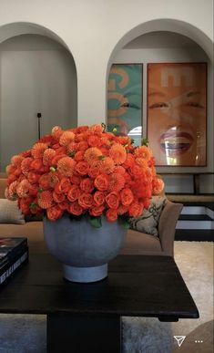 a vase filled with orange flowers sitting on top of a table next to a couch