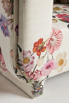 an upholstered chair with colorful flowers on the seat and back cover is sitting on a white surface