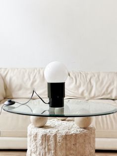 a glass table sitting on top of a wooden floor next to a white couch in a living room