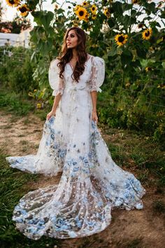 a woman standing in front of sunflowers wearing a white dress