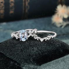 a ring with an oval blue topazte surrounded by leaves on a black velvet surface