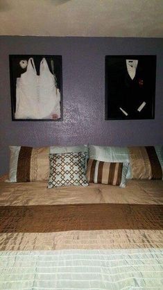 a bed with two pictures hanging on the wall above it and pillows in front of it