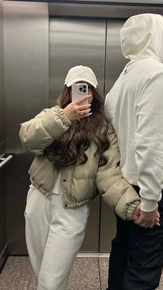 a woman taking a selfie in an elevator with a man wearing a white hoodie