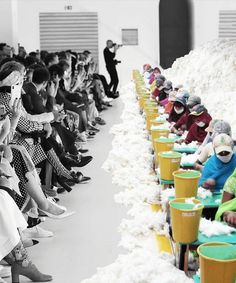 an image of people sitting in front of a row of buckets filled with snow