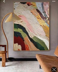 an abstract painting hangs on the wall next to a chair and lamp in a living room