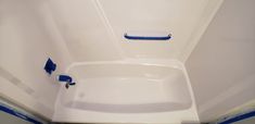 a white bath tub sitting inside of a bathroom next to a shower head and hand rail