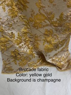 the fabric has gold leaves on it and is white with black lettering that reads, brocade fabric color yellow gold background is champagne