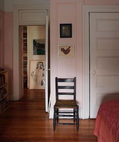 a chair sitting in the middle of a room next to a book shelf and door